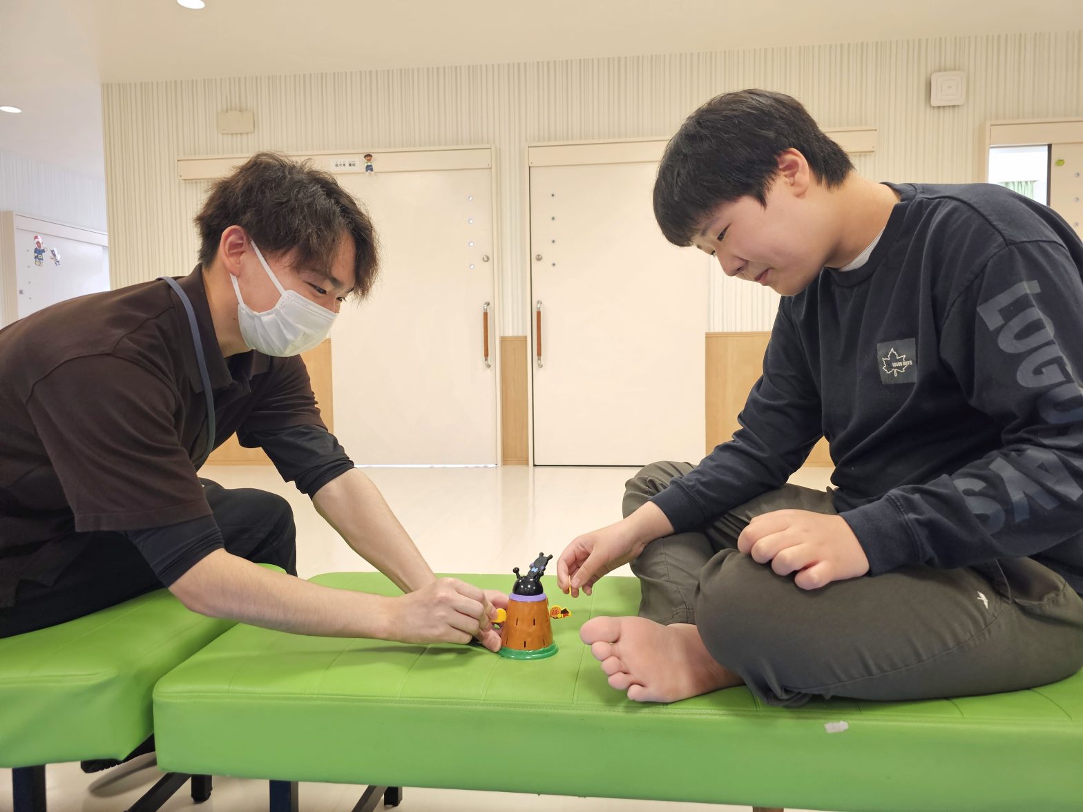 スタッフと入居者がおもちゃで遊ぶレク活動の様子