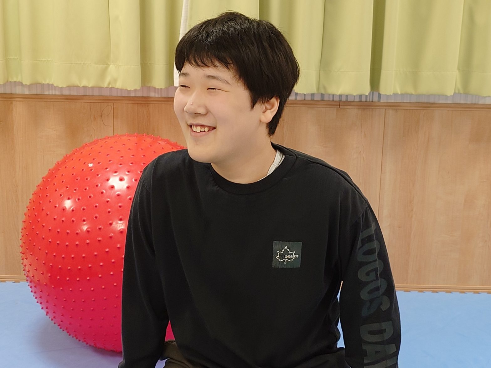 入居者が赤いバランスボールを使用したリハビリ活動風景