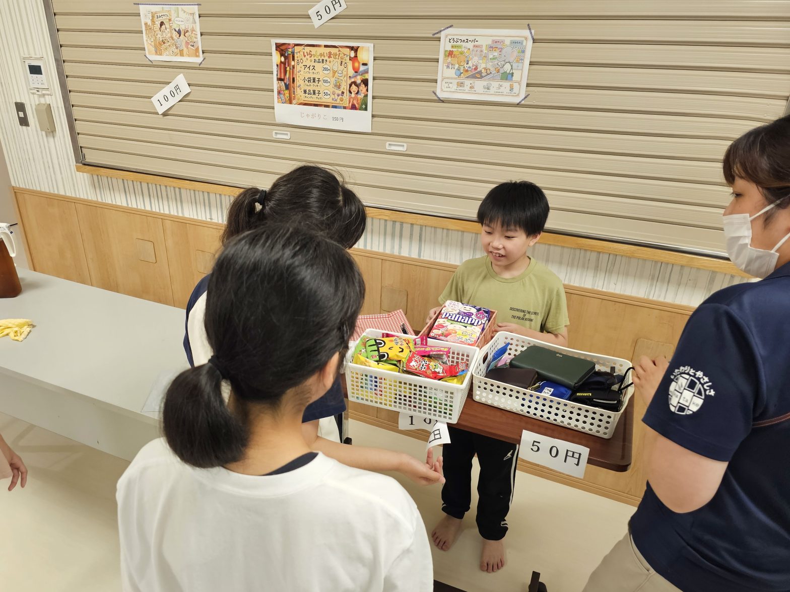 施設内でおもちゃ販売イベントに参加する子どもたちと職員の風景